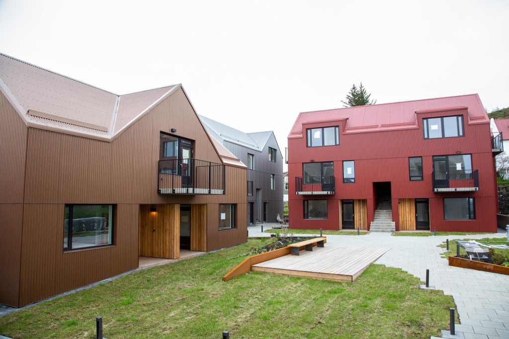 A row of houses with red roofs and green grass in a peaceful neighborhood.