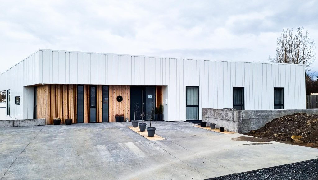 A contemporary white building with a driveway and a pathway leading to its entrance.