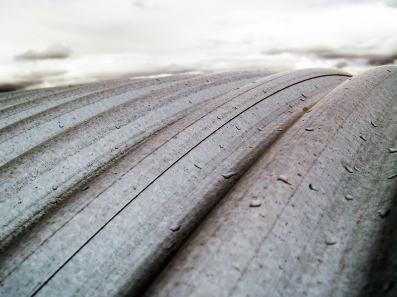 A close-up of a large metal pipe with water droplets, showcasing its texture and moisture.