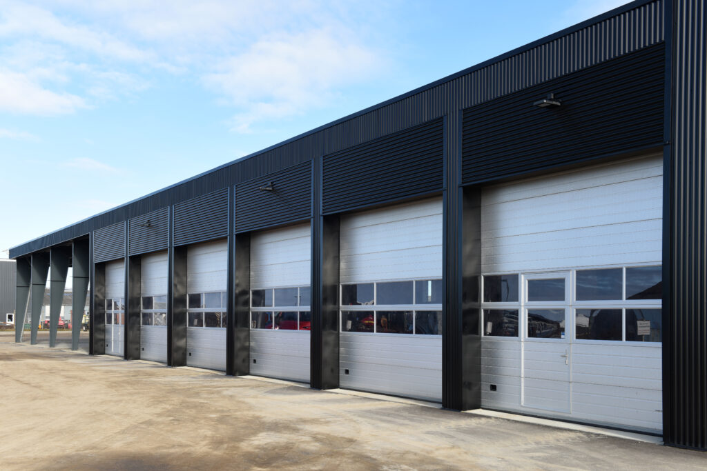 Hvítar iðnaðarhurðir í svartri byggingu