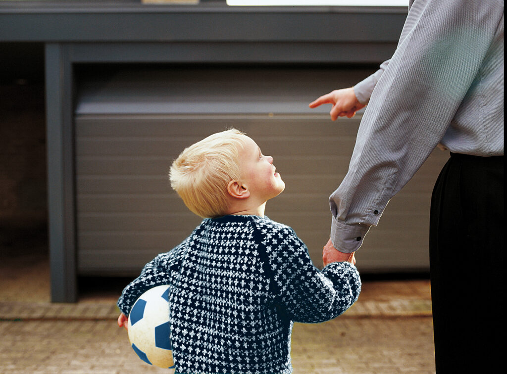 Barn fyrir framan bílskúrshurð sem er að opnast